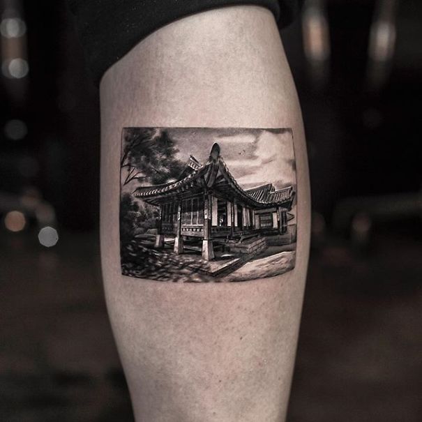 Realistic tattoo of a traditional building, appearing printed on the skin by a Belgian tattooist.