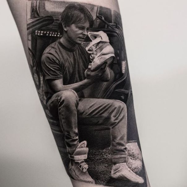 Realistic tattoo resembling a printed image on skin by Belgian tattooist, depicting a man holding shoes.
