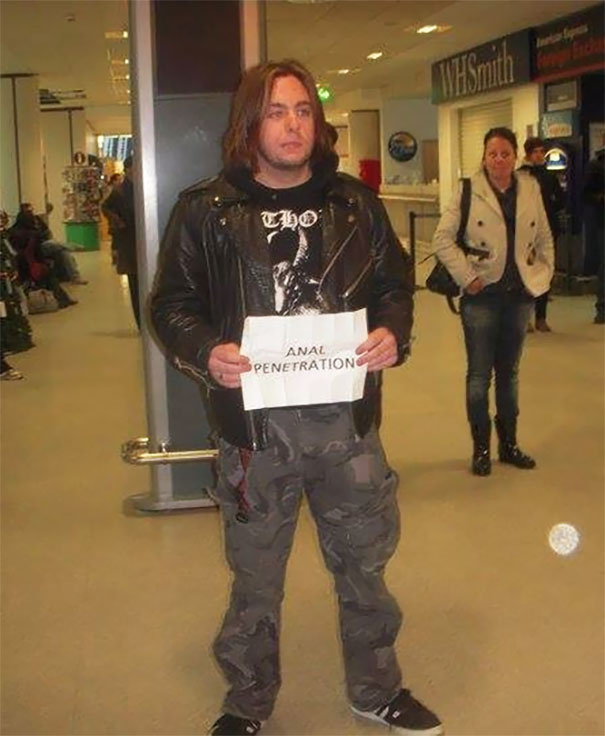 Man holding a funny airport pickup sign inside a terminal.
