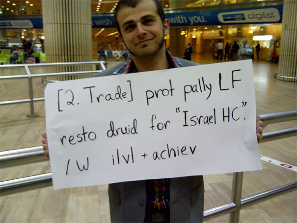 Man holding a funny airport sign with gaming references at the arrivals terminal.