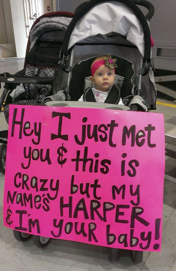 Baby in stroller with funny airport pickup sign reading, "Hey I just met you & this is crazy but my name’s Harper & I’m your baby!"
