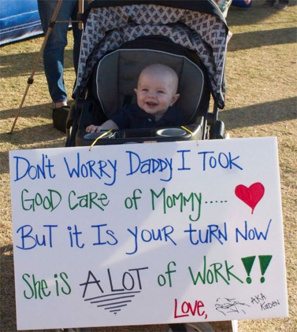 Baby in stroller holding a funny airport pickup sign saying, "Don't worry Daddy, I took good care of Mommy. Your turn now."