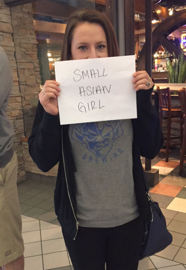 Woman holding a funny airport pickup sign in bustling terminal.