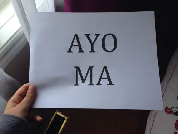 Funny airport pickup sign saying "AYO MA" held by a person.