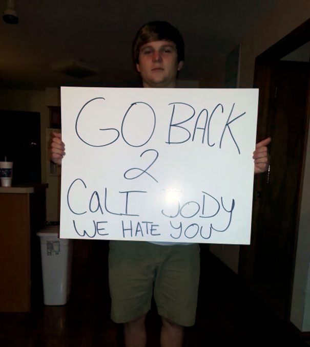 Person holding a funny airport pickup sign that says, "GO BACK 2 CALI JODY WE HATE YOU."