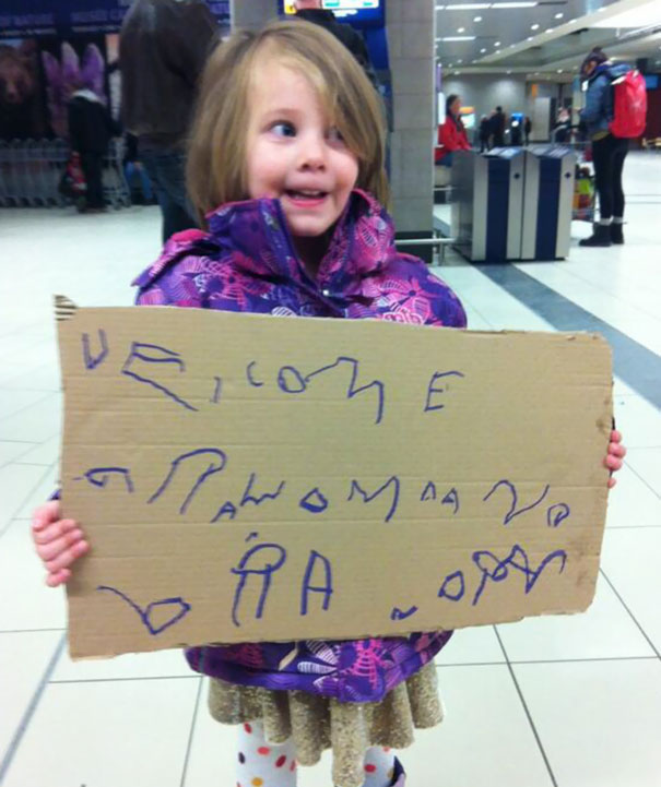 Child holding a funny airport pickup sign with scribbles, making people chuckle.
