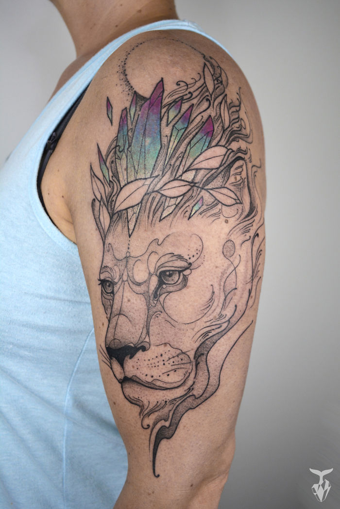 Art Nouveau inspired tattoo featuring a lion with colorful crystal crown on a person's arm.