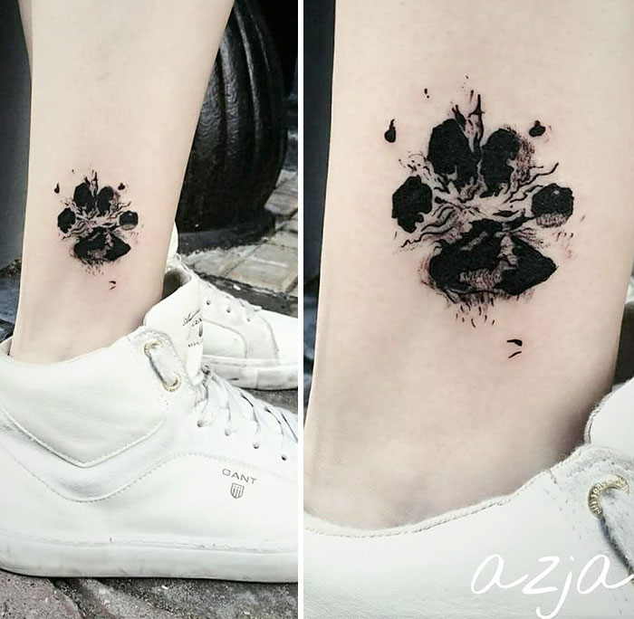 Dog paw print tattoo on ankle next to white sneakers, showcasing pawesome tattoo art.