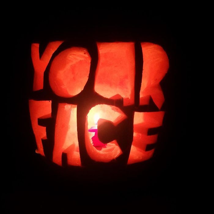 Scary pumpkin carved with "YOUR FACE" illuminated from within.