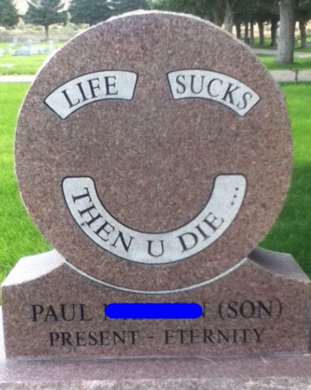 Funny tombstone with an undying humor message saying life s***s then you die in a cemetery setting