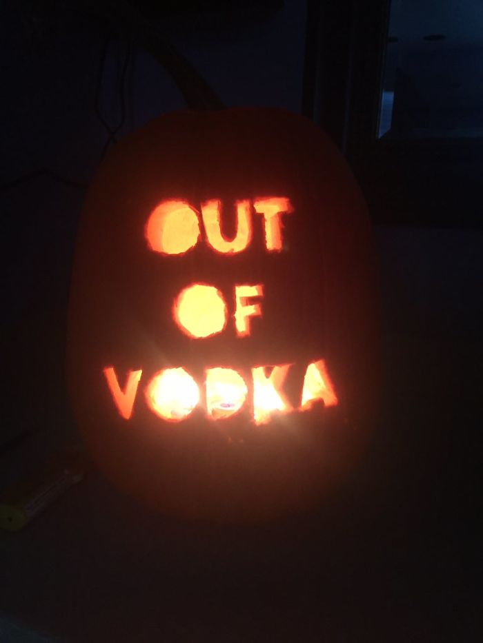 Scary pumpkin carving with "Out of Vodka" phrase illuminated in the dark.