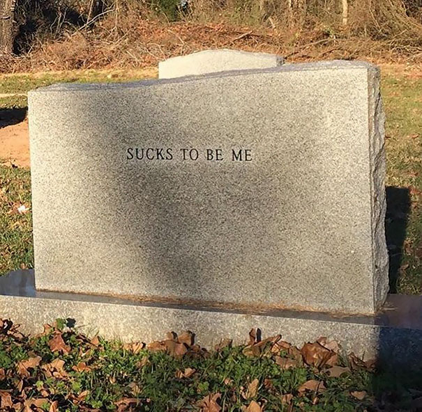 Gray tombstone with funny engraving saying s***s to be me, showcasing humor on a tombstone in a cemetery setting.