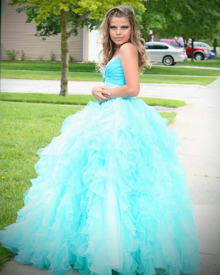 Corey Maison in a light blue dress is standing outside and posing