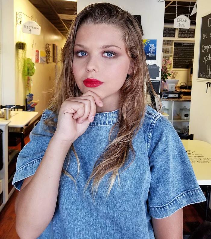 Corey Maison as a girl in denim and with red lipstick posing