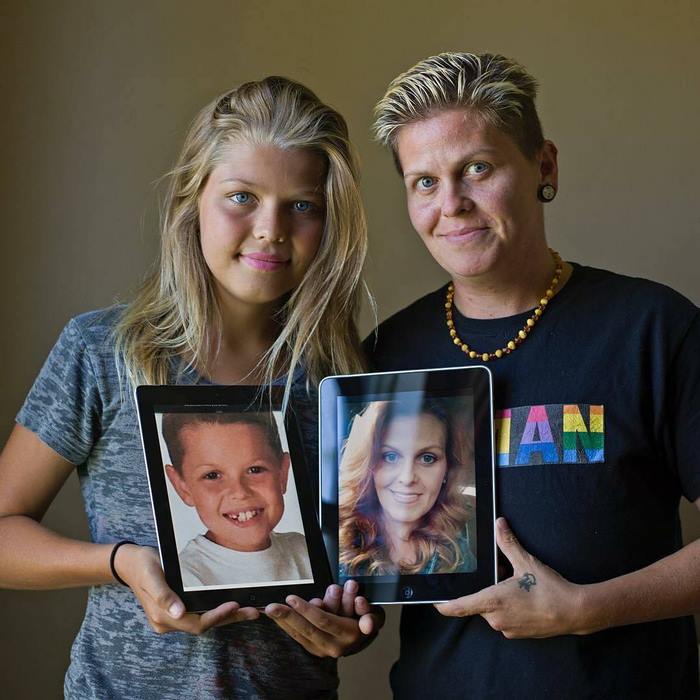 Corey Maison as a woman holding a picture of herself as a boy and her mother Eric standing near as a man and holding a picture of herself as a woman