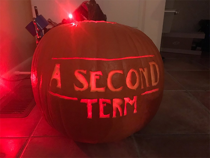 Scary carved pumpkin with "A Second Term" glowing, lit by red lights.