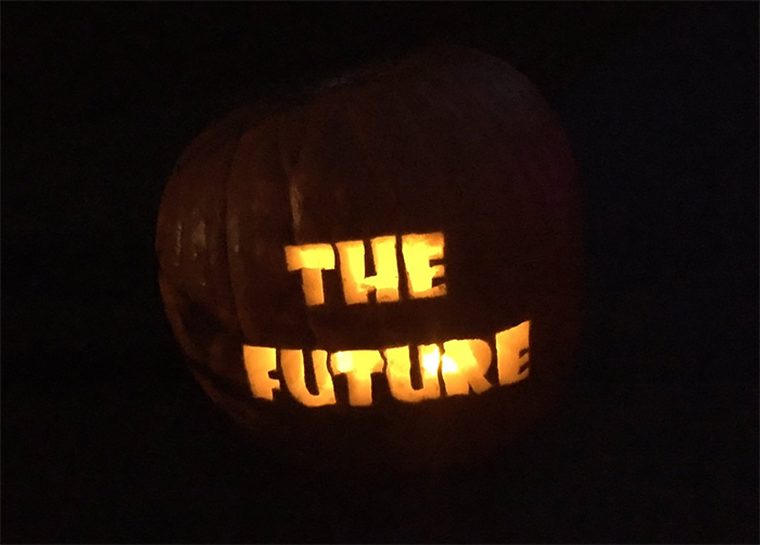 Scary pumpkin carved with glowing "THE FUTURE" text in the dark.