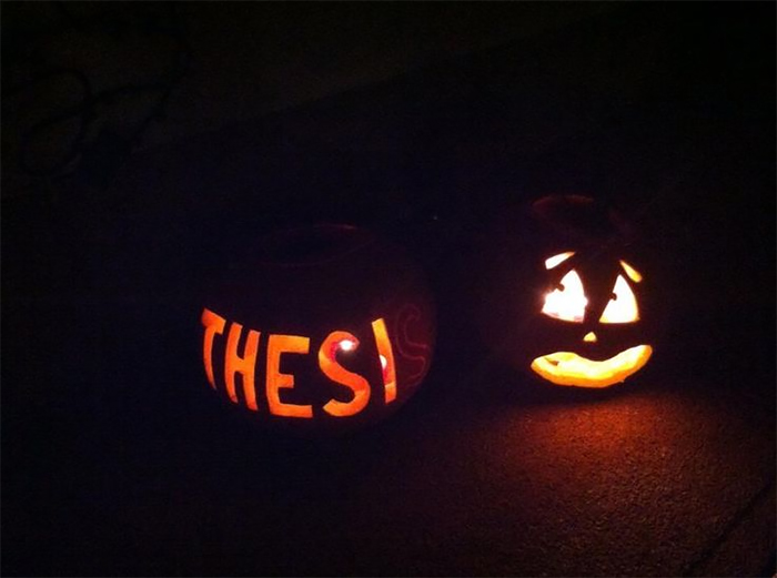 Scary carved pumpkins glowing with "THESIS" text and a sad face.