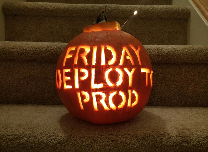 Scariest pumpkin carved with "Friday Deploy to Prod" text, glowing on a staircase.