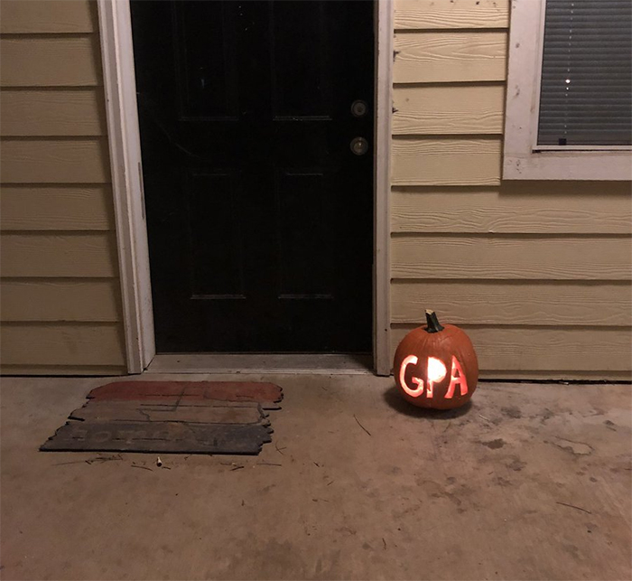 Carved pumpkin with "GPA" design placed by a front door.