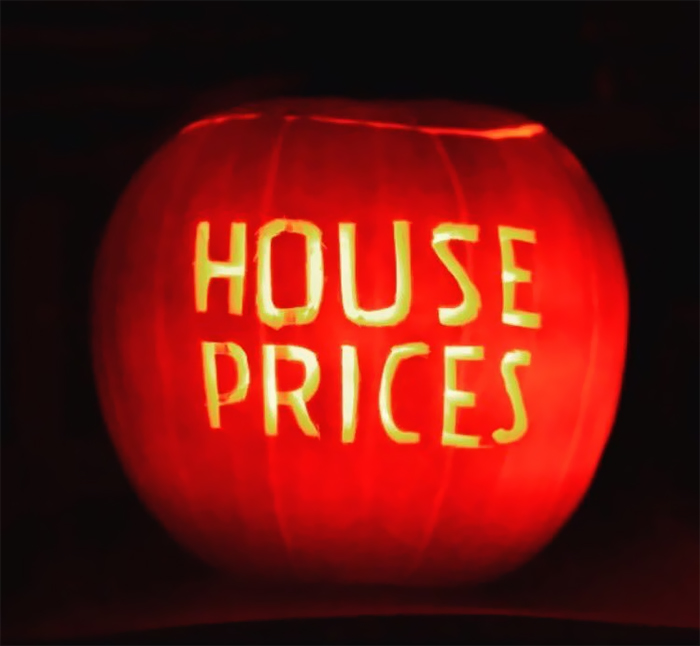 Scary carved pumpkin with "House Prices" text glowing in the dark.