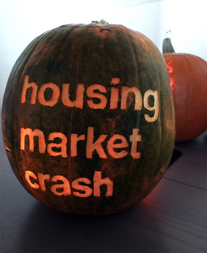 Carved pumpkin with words "housing market crash" glowing, showcasing a creative and scary design.