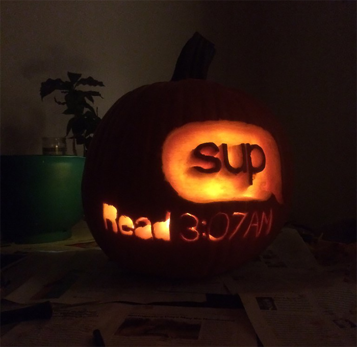 Scary pumpkin carved with the words "sup" and "Read 3:07AM," glowing in the dark.