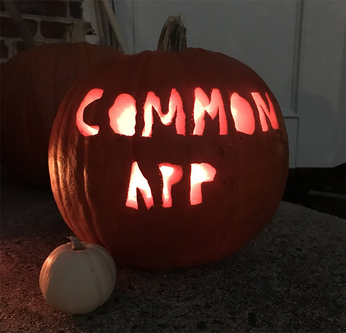 Scary carved pumpkin lit from within, displaying the words "COMMON APP".
