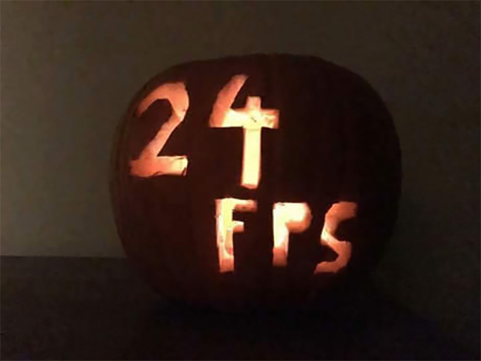 Scary pumpkin carved with "24 FPS" glowing in the dark.