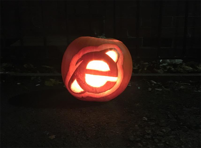Scary pumpkin carved with a classic web browser logo, glowing in the dark.