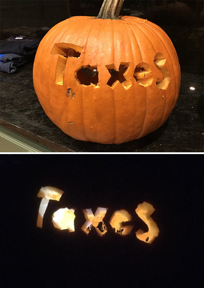Scary carved pumpkin with "Taxes" illuminated.