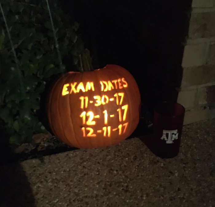 Carved pumpkin with exam dates glowing in the dark, showcasing creative and scary pumpkin art.