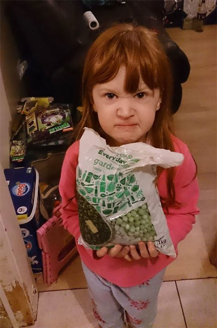 Girl with a grumpy expression holding a bag of frozen peas, illustrating dad jokes taken to another level.