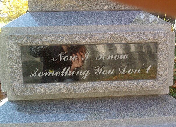 Gray stone tombstone with engraved humorous inscription reflecting funny tombstones by people with undying humor