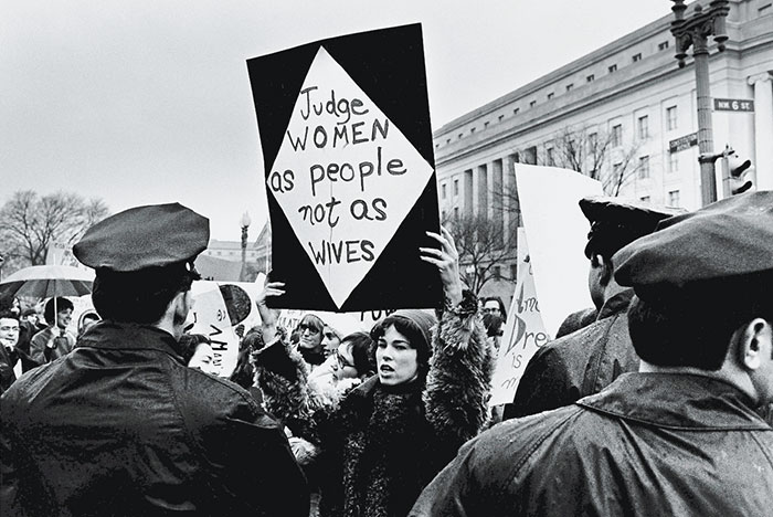 Marilyn Webb Holds Up A Sign As She Protests For Women's Rights In Front Of The Federal Trade Commission Headquarters While Policemen Look On During Richard Nixon's Inauguration Weekend, Washington, Dc, 18-21 January 1969