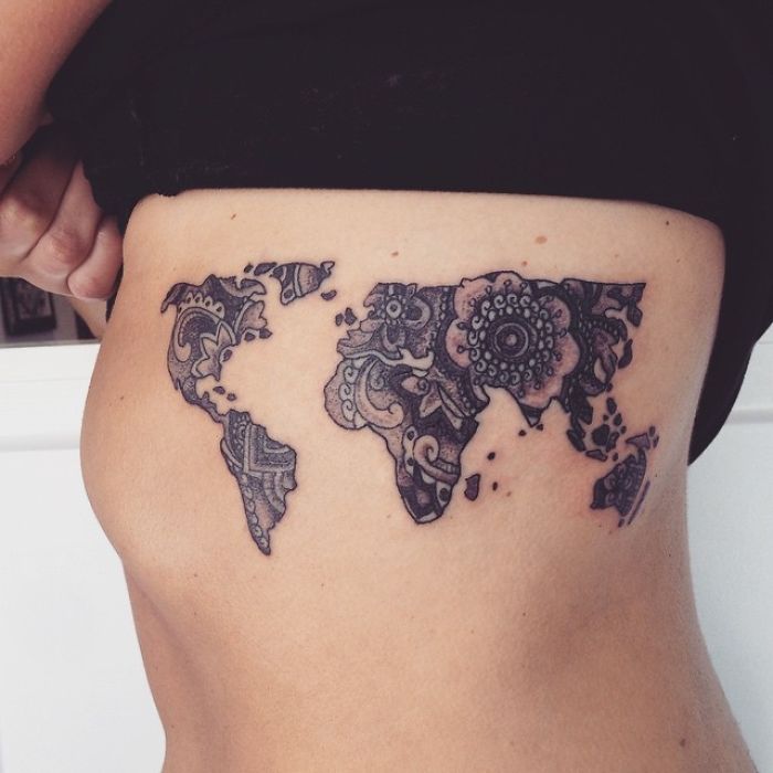 Intricate world map tattoo design on a person's side, symbolizing travel inspiration.