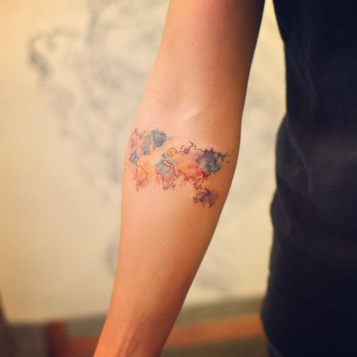 A colorful world map tattoo on an arm, showcasing travel inspiration.