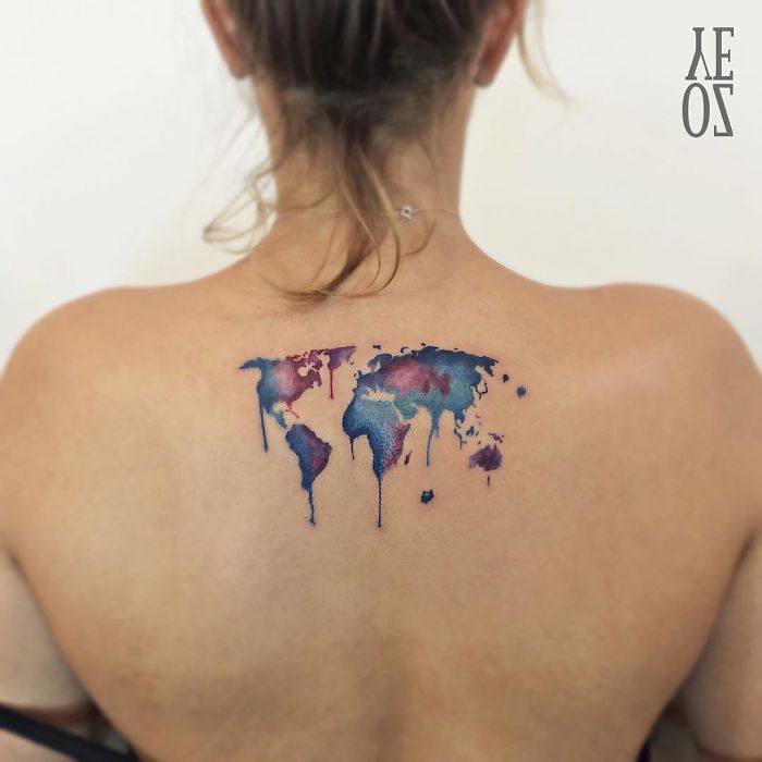 World map tattoo with watercolor effect on a woman's back, a creative travel tattoo design.