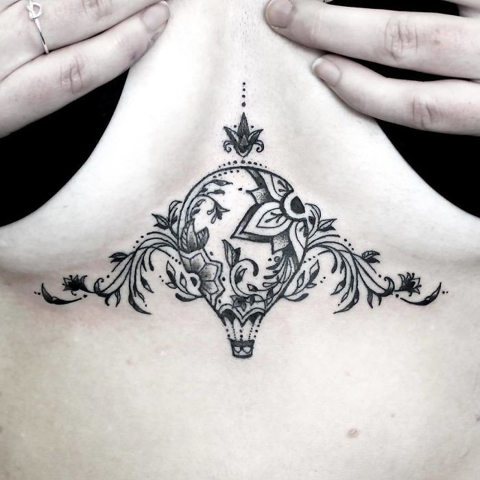 Ornate travel-inspired hot air balloon tattoo on upper back.