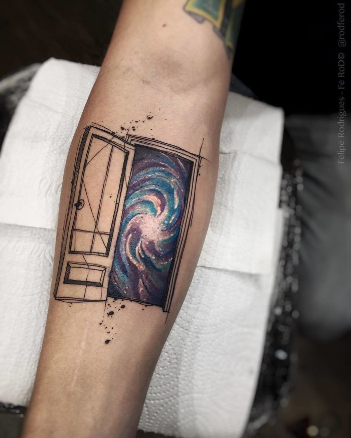 Travel tattoo of an open door with a galaxy, symbolizing adventure and exploration on forearm.