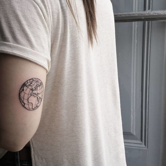 Minimalist globe tattoo on a person's arm, inspired by travel ideas.
