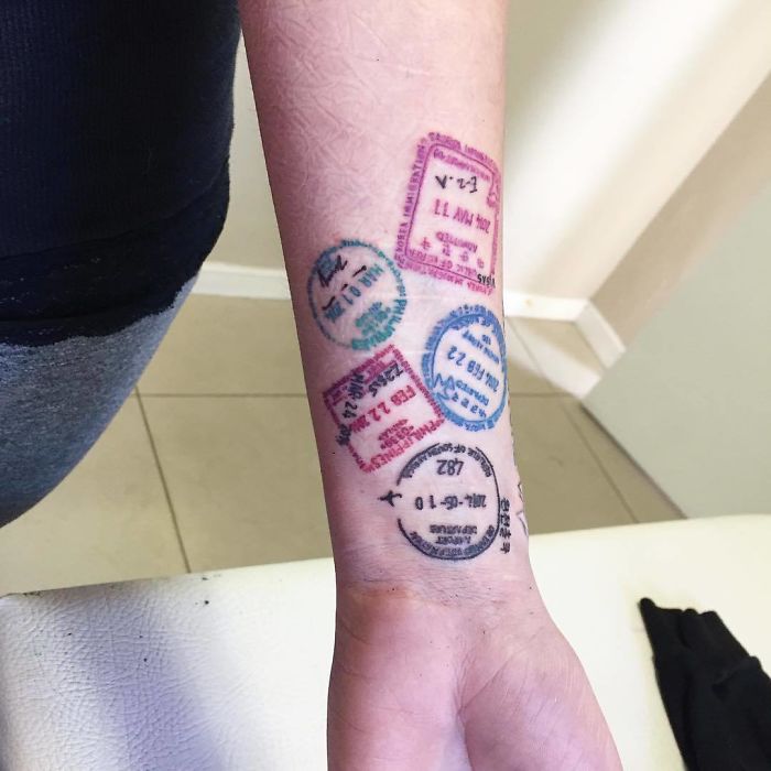 Travel tattoo with passport stamps on a forearm, symbolizing a passion for exploring the world.