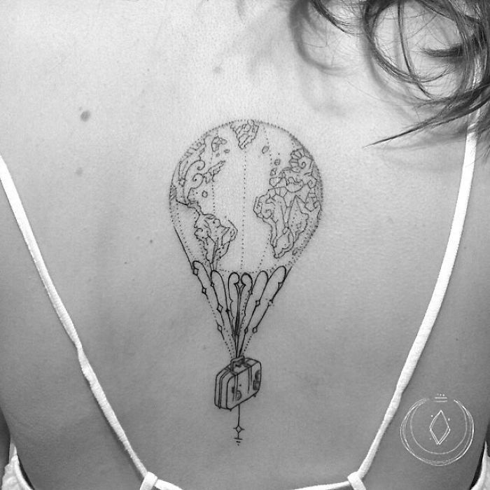 Travel tattoo of a globe balloon with a suitcase basket on a person's back.
