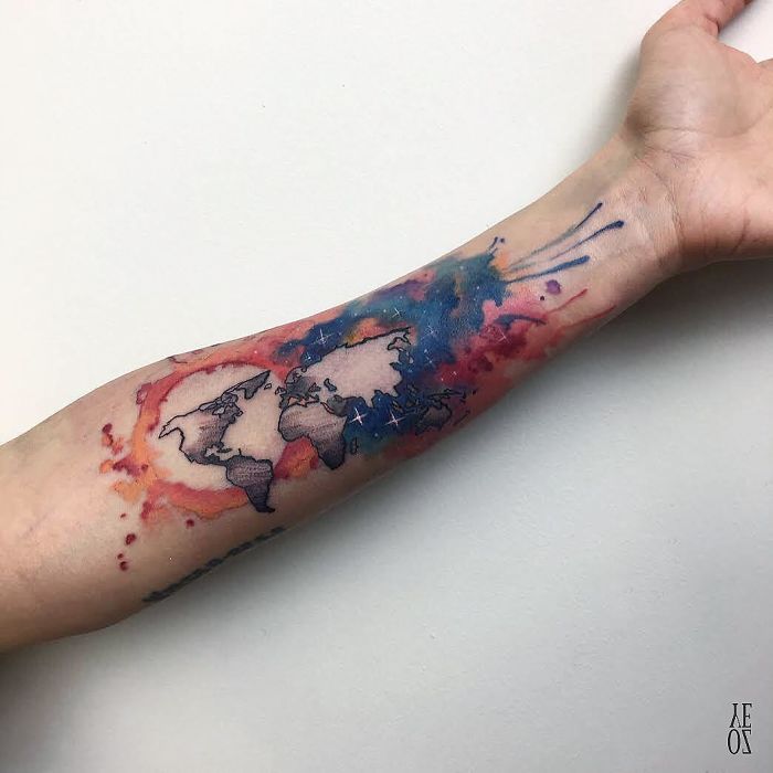 Travel tattoo with a watercolor map design on a forearm, inspired by wanderlust.