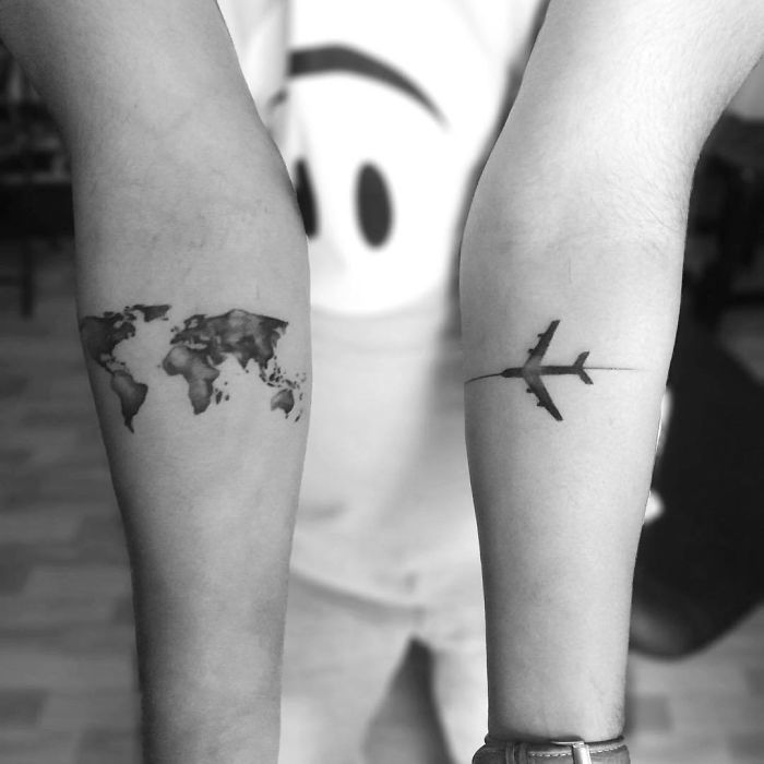 Travel tattoos featuring a world map on one arm and an airplane on the other.