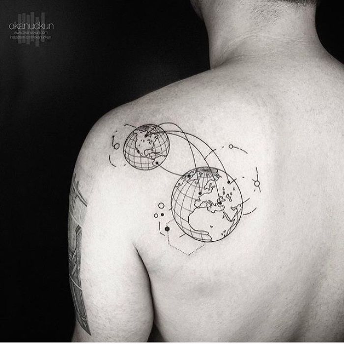 Travel tattoo featuring two globe designs on a person's shoulder, symbolizing exploration and wanderlust.