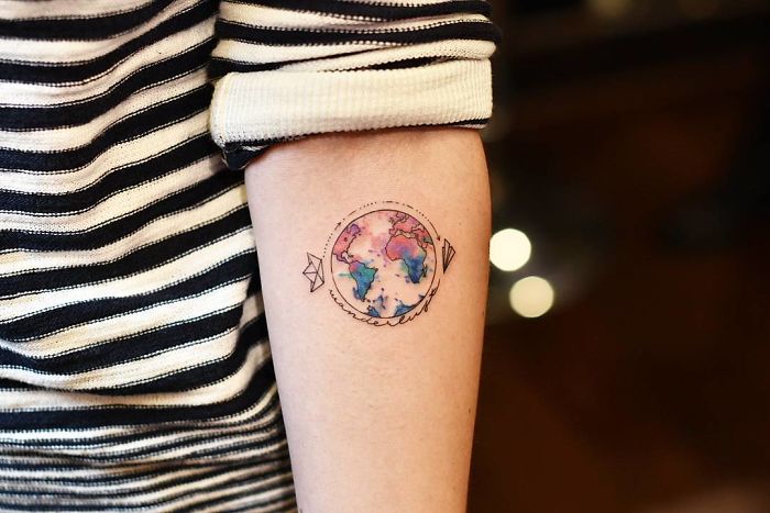 A vibrant world map tattoo on a forearm, symbolizing travel and adventure.