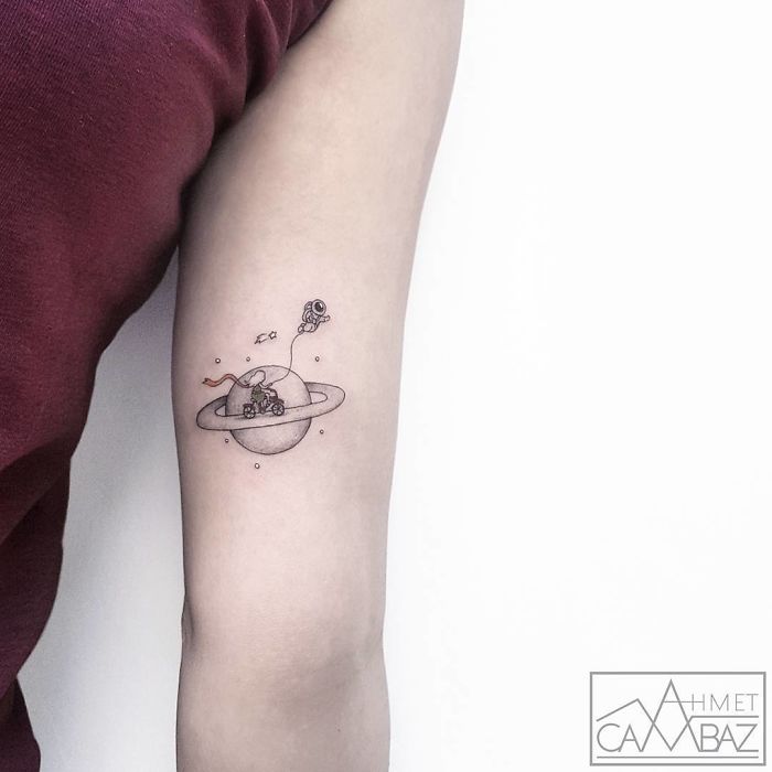 Travel-themed tattoo of a planet with a tiny astronaut, capturing the wanderlust spirit, inked on an arm.