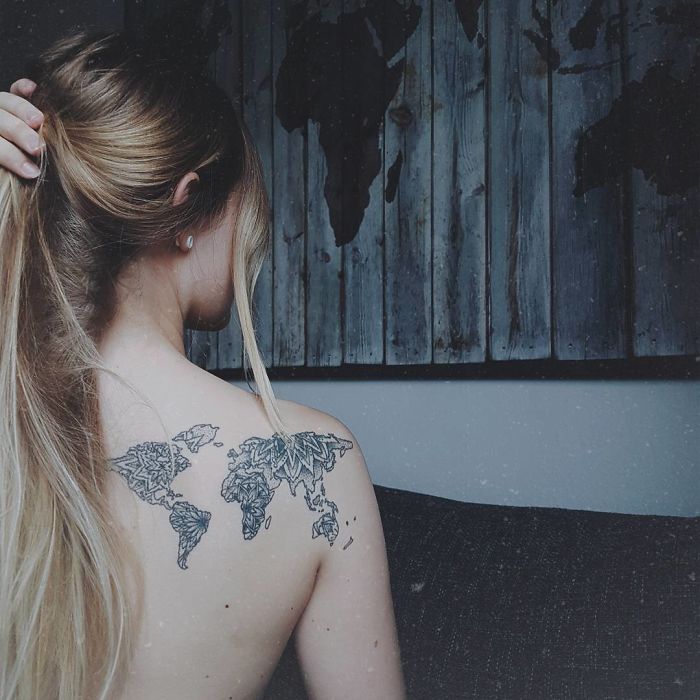 Woman with a detailed world map tattoo on her back, symbolizing travel inspiration.