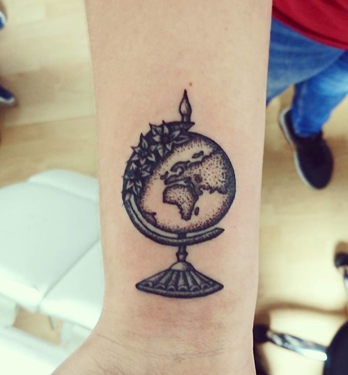 Travel tattoo of a detailed globe on an arm, featuring continents and stars, inspiring wanderlust and adventure.